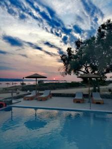 einen Pool mit Stühlen und Sonnenschirmen am Strand in der Unterkunft Acti Plaka Hotel in Plaka