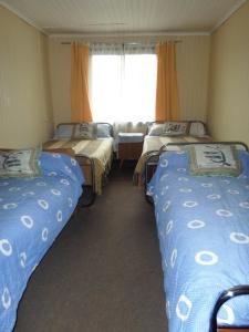 3 camas en una habitación con ventana en Hospedaje Teresita, en Puerto Montt