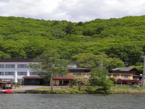 a building on the shore of a lake next to a mountain at Kimimachisou in Chino