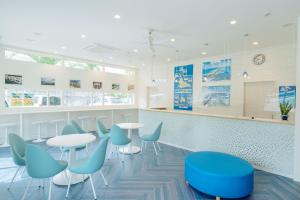 uma sala de espera com mesas e cadeiras azuis em Palm Springs Miyakojima Resort em Ilhas Miyako