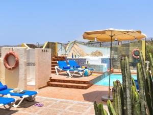 a patio with chairs and an umbrella next to a pool at Rural Village Salobre by VillaGranCanaria in Maspalomas