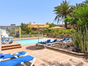 una piscina con sillas y sombrillas azules en Rural Village Salobre, en Maspalomas