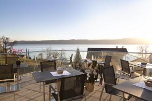 a patio with tables and chairs and a view of the water at Lupinenhotel Bodensee - Apartment mit Seeblick in Sipplingen