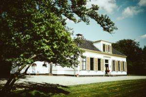 Una casa blanca con un árbol delante. en Klein Soestdijk en Veenhuizen