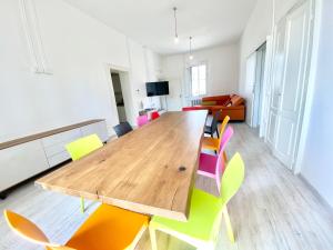 Cette chambre comprend une grande table en bois et des chaises colorées. dans l'établissement BRIBANO HOSTEL & bike sharing-workers and tourists hospitality, à Sedico
