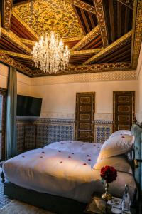 a bedroom with a large bed with a chandelier at Riad Fes - Relais & Châteaux in Fez