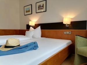 einen Hut auf einem Bett in einem Hotelzimmer in der Unterkunft Lindner's Hotel in Bellheim