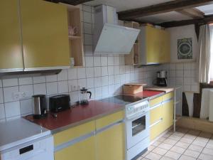 a kitchen with yellow and white cabinets and appliances at Historisches Ferienhaus Zum alten Standesamt in Weenzen +47 photos