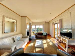 ein Wohnzimmer mit Sofa und Fernseher in der Unterkunft Melkbos Beach Cottage in Melkbosstrand