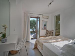 Schlafzimmer mit einem Bett, einem Schreibtisch und einem Fenster in der Unterkunft Infinity sea view cosy villa with private pool in Parikia
