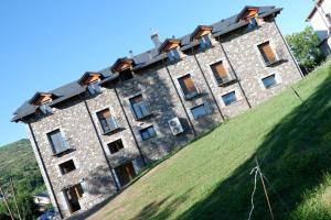a building on top of a grassy hill at Apartamentos Fio de Neu con jardín, gimnasio, barbacoa in Laspaúles