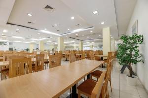 a cafeteria with wooden tables and chairs and plants at Hotel Adria in Biograd na Moru