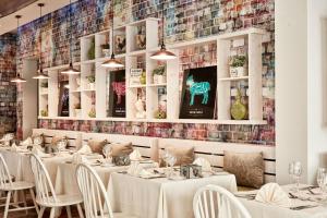 a restaurant with white tables and chairs and a mosaic wall at Atlantica Aeneas Resort in Ayia Napa