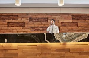 a man talking on a cell phone behind a counter at Atlantica Aeneas Resort in Ayia Napa