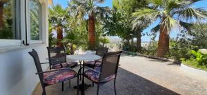 a table and chairs on a patio with palm trees at Christianna House -Villa in Georgioupolis +55 photos