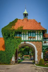 a building with an arch with an ivy at Kadyny Folwark Hotel & SPA in Kadyny