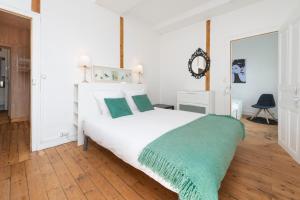 - une chambre avec un lit blanc et une couverture verte dans l'établissement Appartement Coeur de Ville rue Saint-Laud, à Angers