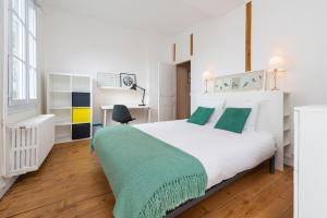 ein weißes Schlafzimmer mit einem großen weißen Bett mit grünen Kissen in der Unterkunft Appartement Coeur de Ville rue Saint-Laud in Angers
