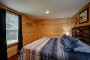 a bedroom with a bed in a wooden room at Dragon's Nest Cabin with Mountain Views in Robbinsville