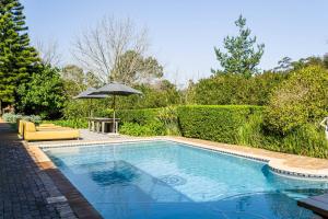 a swimming pool with an umbrella and a chair and a table and an umbrella at Silver Forest Boutique Hotel and Spa in Somerset West