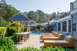 a patio with chairs and an umbrella and a pool at Silver Forest Boutique Hotel and Spa in Somerset West
