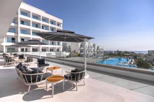 a balcony with tables and chairs and an umbrella at Atlantica Aqua Blue in Protaras