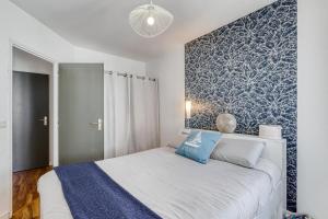 a bedroom with a white bed with a blue accent wall at Maison Dany in Salles-sur-Mer