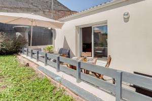 a porch with a fence and an umbrella at Maison Dany in Salles-sur-Mer