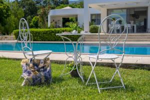 two chairs and a table in the grass near a pool at Villa Syndriani in Paradeísi