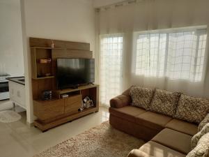 ein Wohnzimmer mit Couch und Flachbildfernseher in der Unterkunft Apartamento Turismo 2 quartos em Águas de Lindóia, Natureza!!!! in Águas de Lindóia