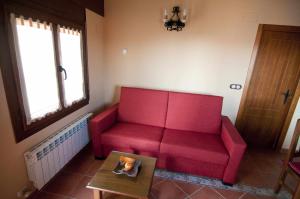 Valbona的住宿－Apartamentos Turisticos Sanahuja，客厅里一张红色的沙发,配有桌子