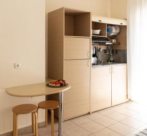 a kitchen with a table and two stools and a small table with fruit on at Thalassenia Studios & Apartments 3 in Hanioti