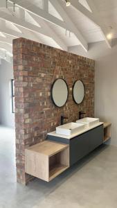 a brick wall with two sinks and two mirrors at Comfort in Langebaan in Langebaan