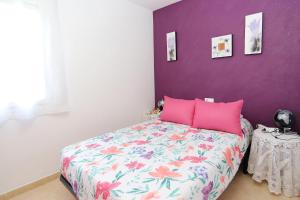 a bedroom with a bed with a purple wall at AT131 Aire acondicionado, comunidad con piscina, playa a 800m in Creixell +18 photos