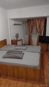 een groot bed met een houten frame in een kamer bij HOTEL modern / Imobiliare Garcea Titu in Titu