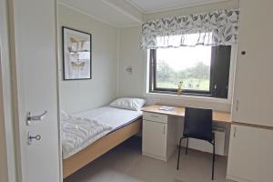 ein kleines Schlafzimmer mit einem Schreibtisch, einem Bett und einem Fenster in der Unterkunft STF Station Linné in Färjestaden