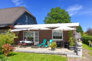 a house with a patio with chairs and umbrellas at Haus Sonne & Meer in Esens