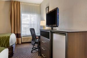 a hotel room with a desk with a television on it at Comfort Inn Wings Stadium in Kalamazoo