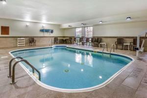 una piscina en una habitación de hotel con mesas y sillas en Comfort Inn Wings Stadium en Kalamazoo