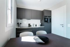 a kitchen with black cabinets and a table and chairs at Locarno Studios by Quokka 360 - in the centre of Locarno in Locarno