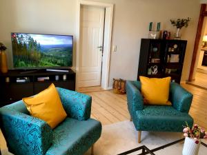 a living room with two blue chairs and a flat screen tv at Schöne Ferienwohnung am Mathildenbrunnen in Quedlinburg