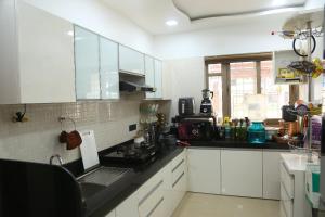 a kitchen with white cabinets and a black counter top at Monty Villa 3Bhk in Lonavala