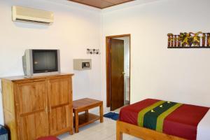 Habitación con TV, cama y armario. en Flamboyan Hotel, en Kuta