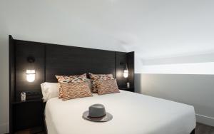 a hat is sitting on a bed with pillows at TOC Hostel Malaga in Málaga +47 photos