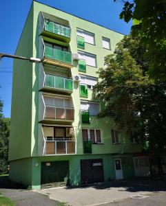 Center Home Apartman في أورشازا: مبنى اخضر نوافذه جانبيه