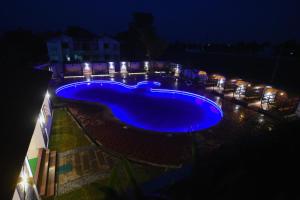 ein großer blauer Pool in der Nacht mit Lichtern in der Unterkunft DVG Socials Retreat in Davanagere