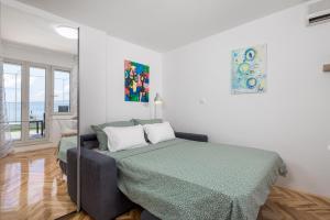 ein weißes Schlafzimmer mit einem Bett mit einer grünen Decke in der Unterkunft Studio apartman Rozi in Opatija