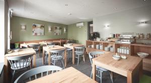 a restaurant with wooden tables and chairs and a kitchen at Hotel Landlust St. Martin in Sankt Martin