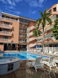 a hotel with a swimming pool with chairs and a building at Zahira Hotel Melgar in Melgar