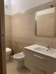 a bathroom with a sink and a toilet and a mirror at Le Stanze della Braceria Calabrese in Scilla